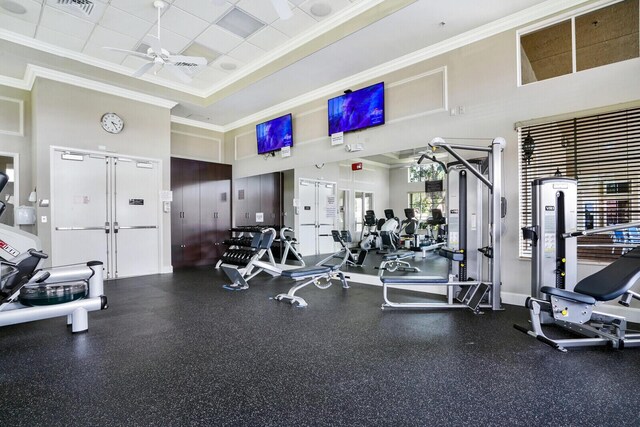 workout area featuring ceiling fan, ornamental molding, a raised ceiling, and a paneled ceiling