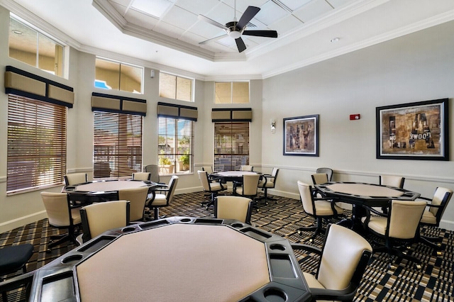 dining room featuring ceiling fan, a towering ceiling, baseboards, ornamental molding, and a raised ceiling