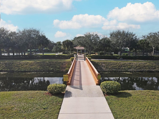 view of dock with a water view and a lawn