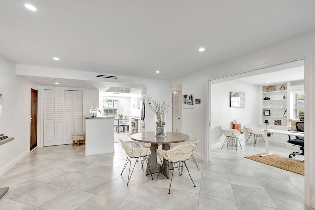 dining room featuring built in shelves, sink, and light tile patterned floors