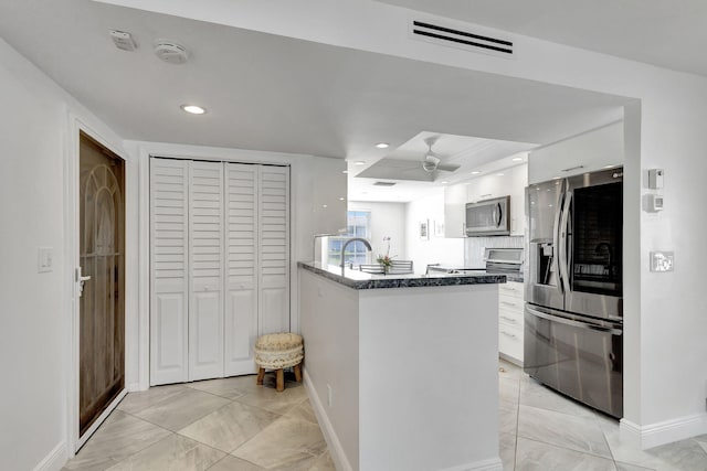 kitchen with sink, ceiling fan, appliances with stainless steel finishes, white cabinetry, and decorative backsplash