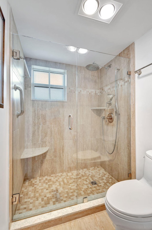 bathroom featuring a shower with shower door and toilet