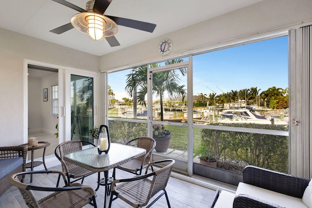 sunroom / solarium with ceiling fan and a water view