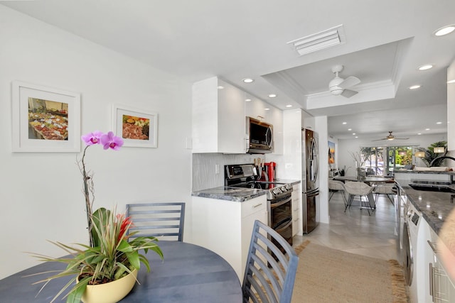 kitchen with sink, white cabinetry, appliances with stainless steel finishes, a raised ceiling, and decorative backsplash