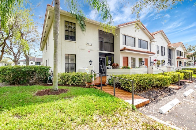 view of front of home featuring a front lawn, fence, a tile roof, and stucco siding