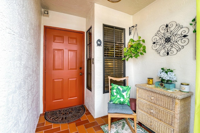 view of exterior entry featuring stucco siding and covered porch