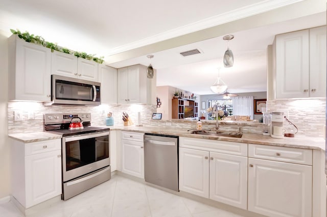 kitchen featuring a sink, stainless steel appliances, white cabinetry, decorative backsplash, and visible vents