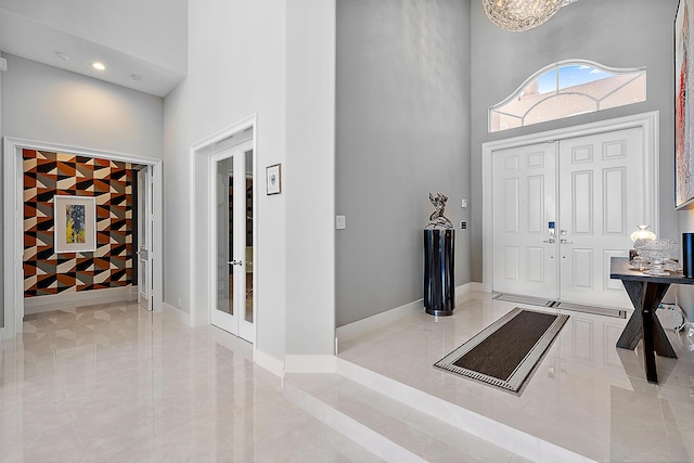 foyer with a high ceiling, a chandelier, and french doors