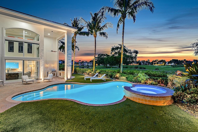 pool at dusk featuring an in ground hot tub, a yard, and a patio