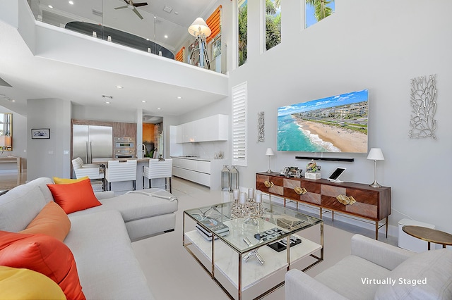 living room with a towering ceiling and ceiling fan