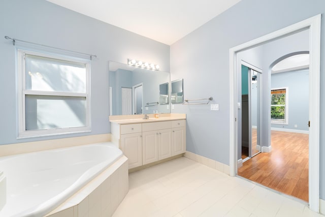 bathroom with vanity and tiled bath