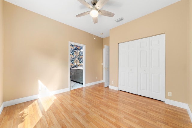 unfurnished bedroom featuring a closet, connected bathroom, ceiling fan, and light hardwood / wood-style flooring