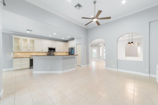 kitchen with appliances with stainless steel finishes, a center island, wine cooler, ornamental molding, and decorative backsplash