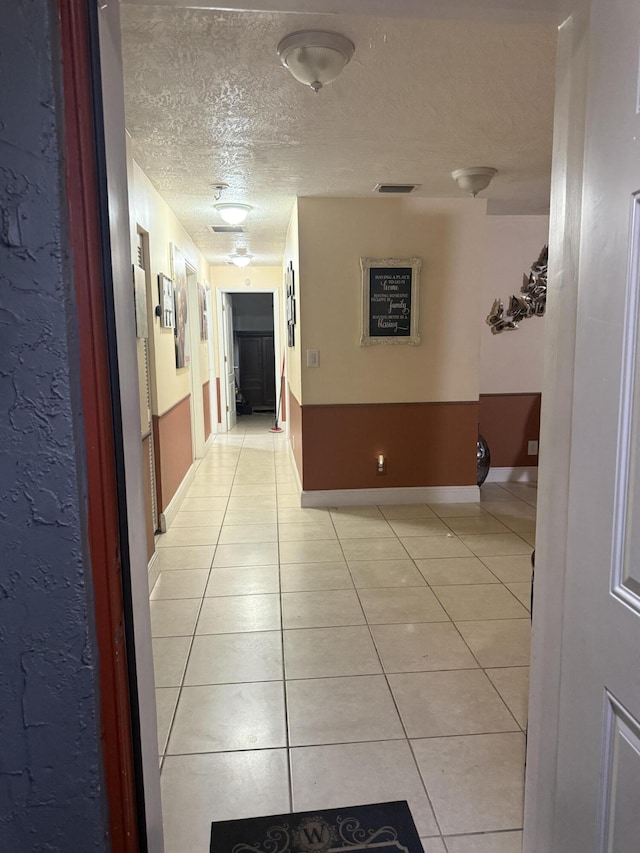 hallway featuring light tile patterned flooring and a textured ceiling