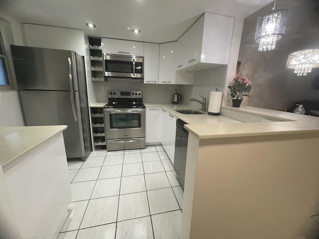 kitchen featuring sink, white cabinetry, hanging light fixtures, appliances with stainless steel finishes, and kitchen peninsula