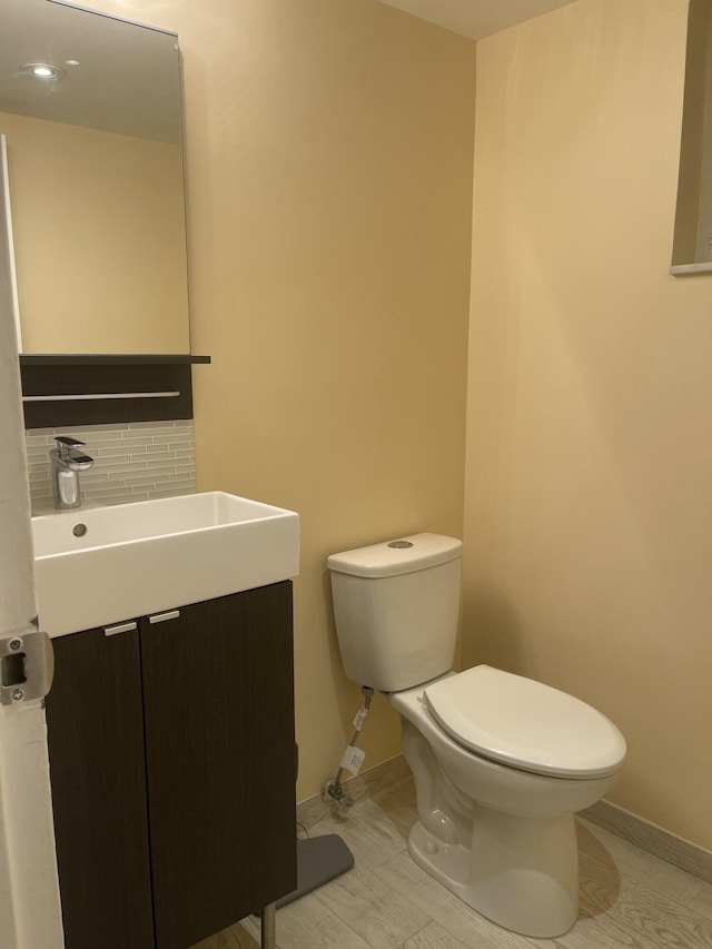 bathroom featuring vanity, decorative backsplash, and toilet