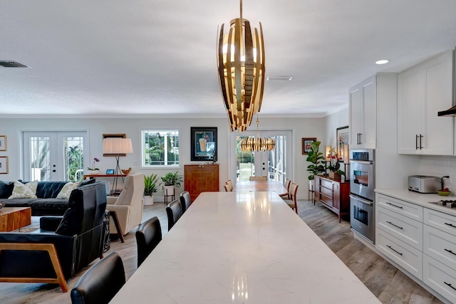 dining space featuring visible vents, light wood-style flooring, crown molding, french doors, and recessed lighting