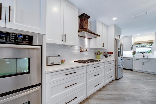 kitchen with custom exhaust hood, stainless steel appliances, tasteful backsplash, light countertops, and white cabinetry