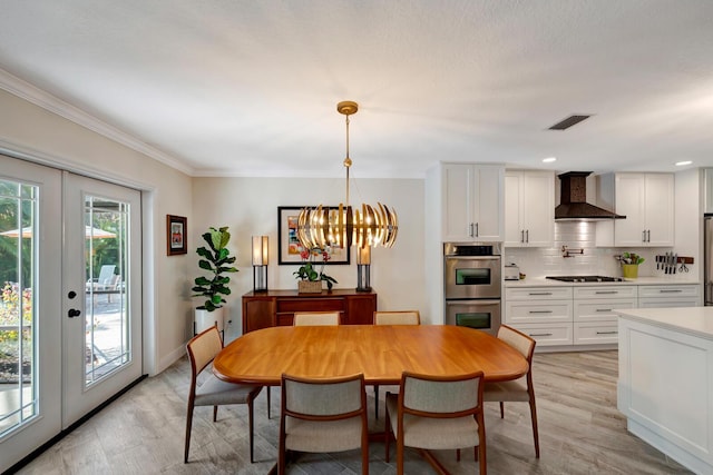 dining area featuring light wood finished floors, visible vents, crown molding, french doors, and a chandelier