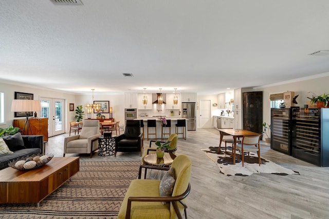 living room featuring ornamental molding, french doors, visible vents, and light wood-style floors