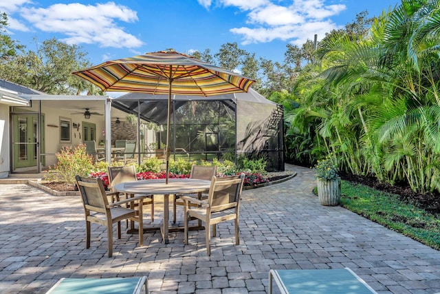 view of patio with outdoor dining area, a lanai, and a ceiling fan