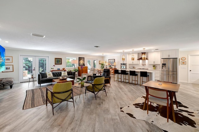 living area with light wood-type flooring, french doors, visible vents, and baseboards