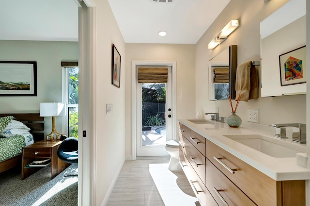 bathroom with baseboards, a sink, toilet, and double vanity