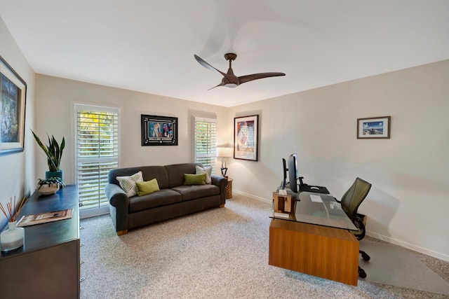 office featuring light colored carpet, ceiling fan, and baseboards