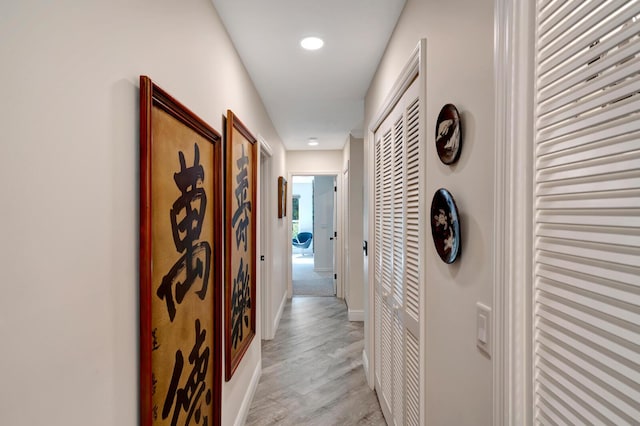 hallway featuring light wood-type flooring and baseboards