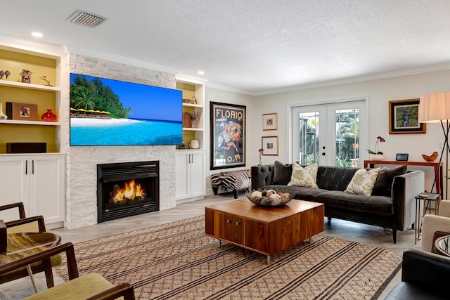 living area with built in features, visible vents, a textured ceiling, and french doors