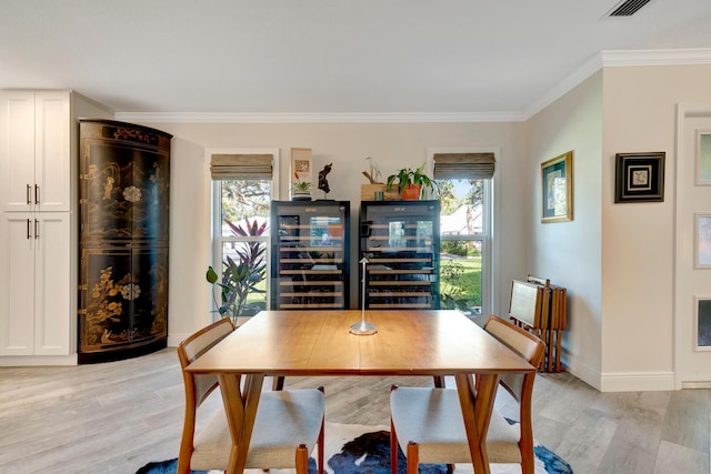 dining area featuring light wood-type flooring, beverage cooler, ornamental molding, and baseboards