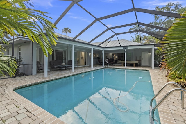 view of pool with outdoor lounge area, a patio, and glass enclosure