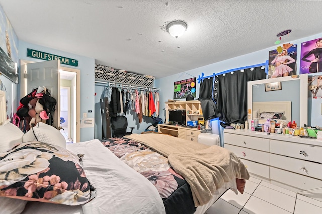 bedroom with a closet, a textured ceiling, and light tile patterned flooring