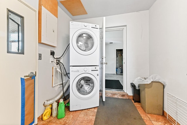 clothes washing area featuring stacked washer / drying machine and electric panel