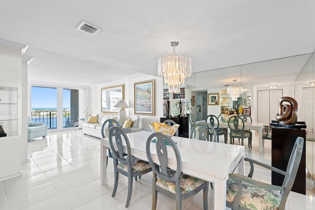 tiled dining area featuring a water view, ornamental molding, and a notable chandelier