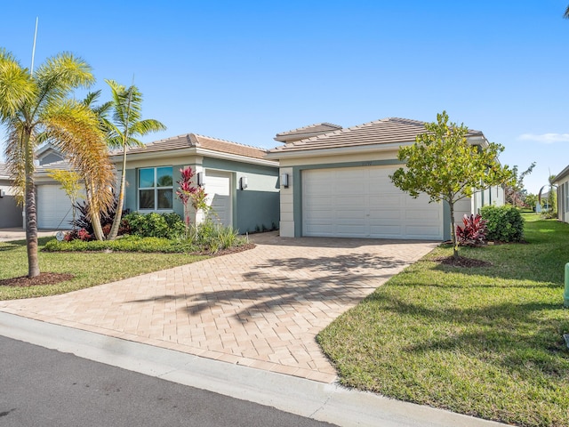 view of front of property featuring stucco siding, decorative driveway, a front yard, a garage, and a tiled roof