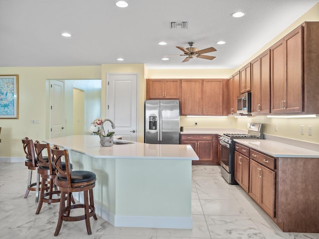 kitchen featuring a center island with sink, recessed lighting, appliances with stainless steel finishes, marble finish floor, and a sink