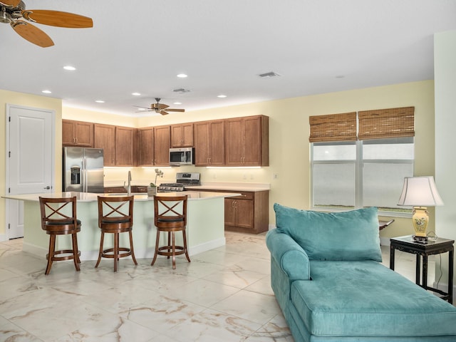 kitchen featuring a breakfast bar area, visible vents, a sink, stainless steel appliances, and marble finish floor