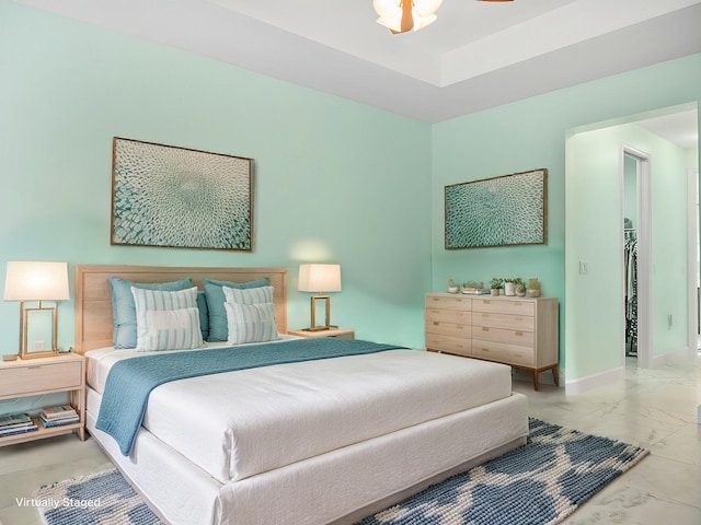 bedroom with a raised ceiling, a spacious closet, baseboards, and marble finish floor