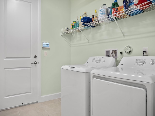 laundry room with light tile patterned floors, baseboards, washing machine and dryer, and laundry area