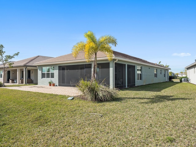 rear view of property featuring stucco siding, a patio, a lawn, and a sunroom