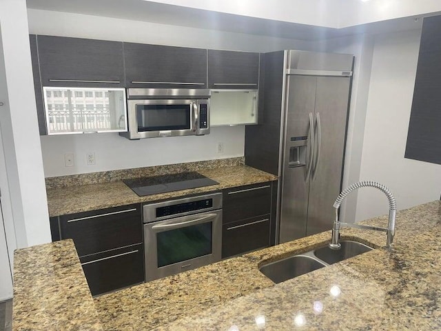 kitchen featuring appliances with stainless steel finishes, sink, and light stone counters