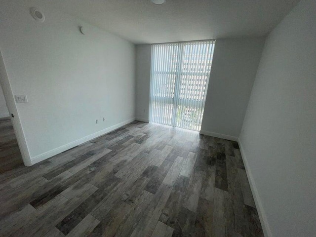 spare room with dark wood-type flooring and expansive windows