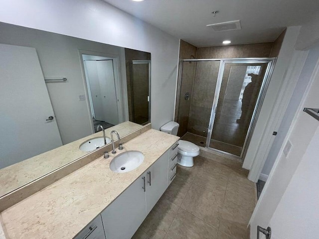 bathroom with tile patterned flooring, vanity, a shower with shower door, and toilet