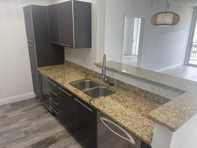 kitchen with sink, dishwasher, dark hardwood / wood-style floors, light stone countertops, and kitchen peninsula