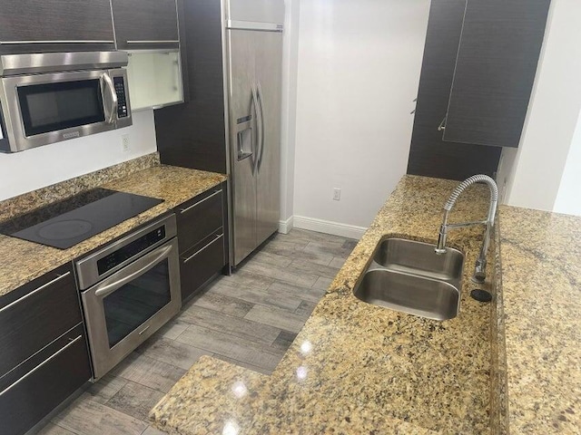 kitchen featuring light stone counters, sink, and stainless steel appliances