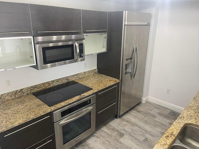 kitchen with light stone counters, stainless steel appliances, and light hardwood / wood-style flooring