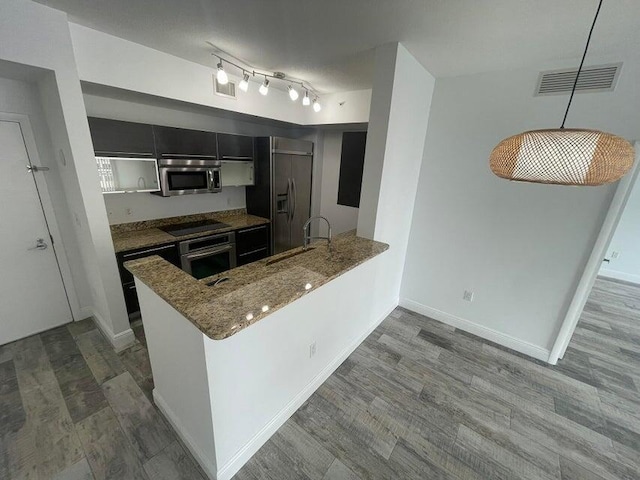 kitchen featuring kitchen peninsula, decorative light fixtures, sink, black appliances, and light wood-type flooring