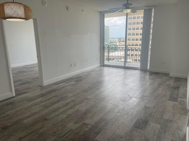 unfurnished room featuring ceiling fan, a wall of windows, and dark hardwood / wood-style flooring