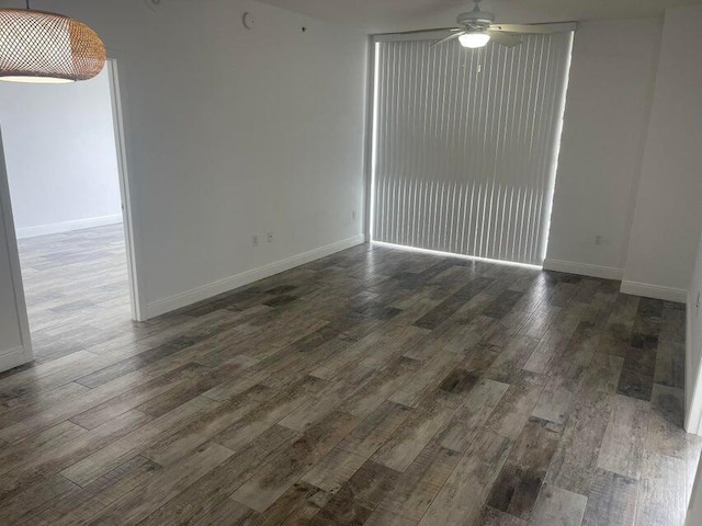 empty room with ceiling fan and dark hardwood / wood-style flooring